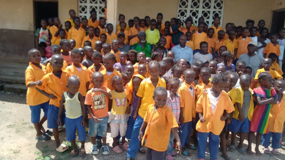 Schoolchildren in orange uniforms gathered outside their school in Sierra Leone