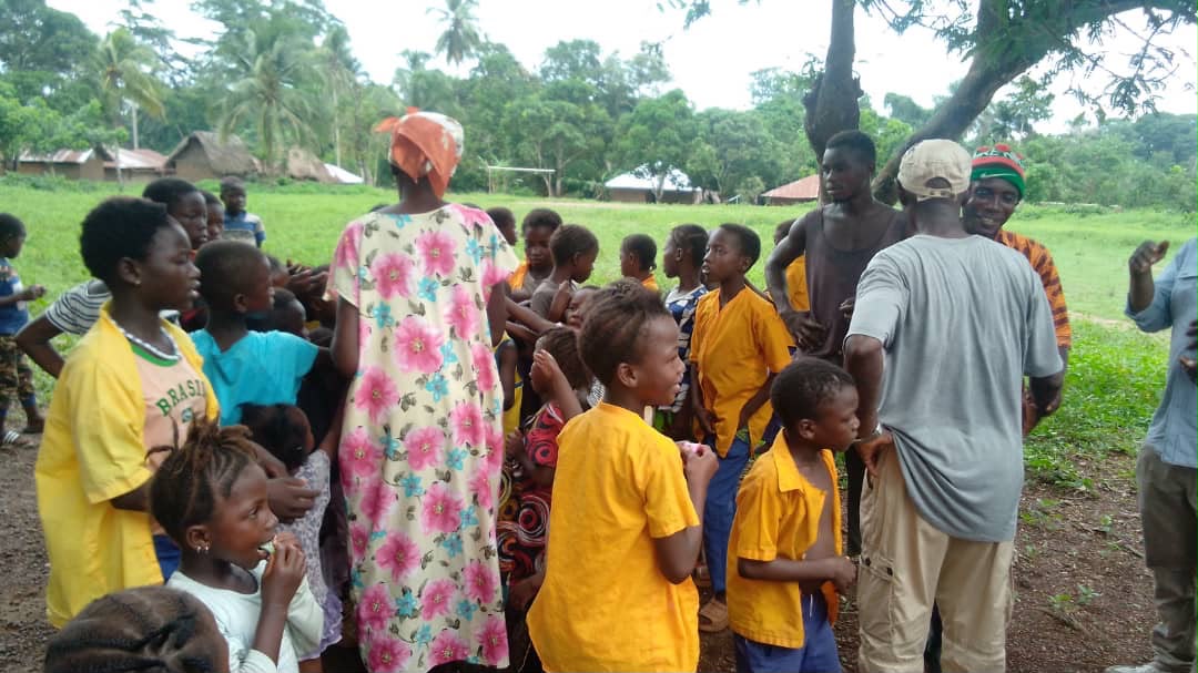 Children and community members gathered together in a rural Sierra Leone village