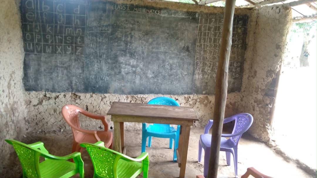 A makeshift classroom with a chalkboard and plastic chairs in Sierra Leone
