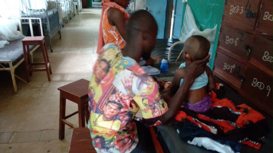 A caregiver tending to a hospitalized child in a Sierra Leone hospital ward